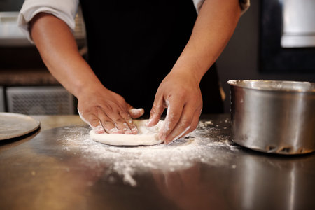 Closeup image of baker kneading small piece of dough