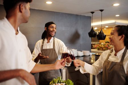 Team of joyful cooks drinking wine when celebrating restaurant openingの写真素材