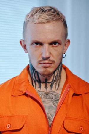 Portrait of serious criminal in orange uniforrm ready for imprisonmentの写真素材