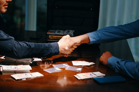 Cropped image of drug dealer and buyer shaking hands over table with money and small bags with tabletsの写真素材