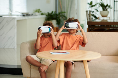 Siblings in headsets playing virtual reality game at homeの写真素材