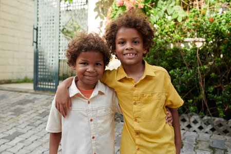 Portrait of hugging brothers standing in backyard and smiling at cameraの写真素材