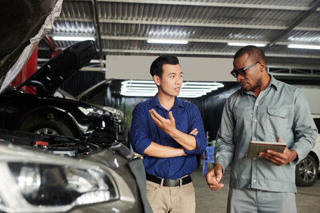 Car owner telling mechanic what problems he has with his carの写真素材