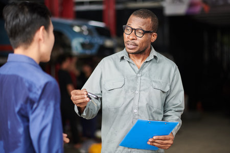 Car mechanic talking to client explaining what parts should be ordered