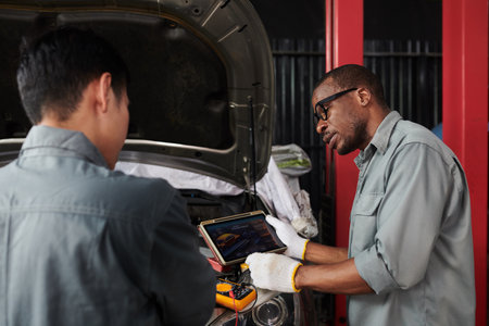Mechanics using application to check if car parts and engine works goodの写真素材
