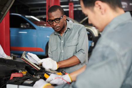 Team of mechanics using multimeter when checking car engineの写真素材