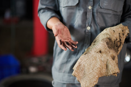 Mechanic wiping hands with soft cloth after changing motor oil in car of clientの写真素材