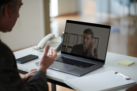 Businessman talking to coworker in online meetingの写真素材