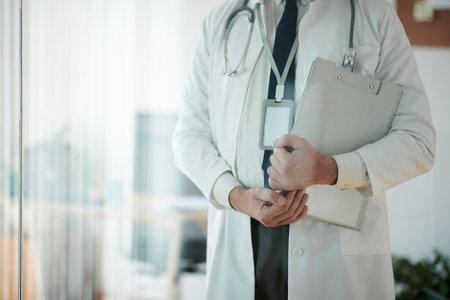 Cropped image of doctor in labcoat standing in medical office and holding clipboardの写真素材