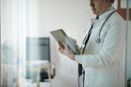 Cropped image of physician filling document on tablet computerの写真素材
