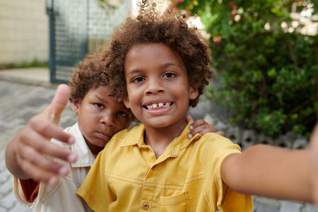 Preteen boy taking selfie with younger brother or filming videoの写真素材