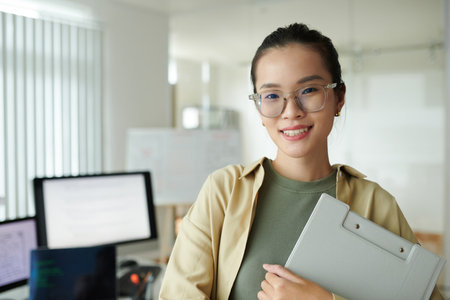 Portrait of joyful young software developer standing at her new workplaceの写真素材