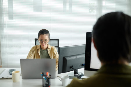 Pensive software developer working on laptop at office desk