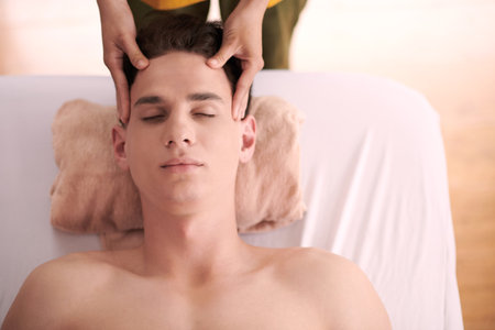Young man getting head massage in spa salon, view from aboveの写真素材