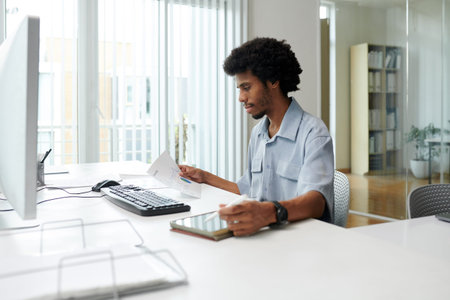 Young Black businessman working with documents at office desk