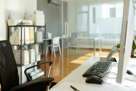 Empty chair next to computer desk in office of modern companyの写真素材