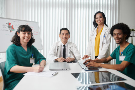 Happy medical team sitting at big table in office of clinicの写真素材