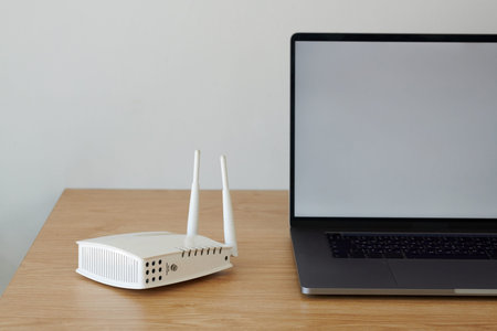 Wifi router next to opened laptop on wooden desk