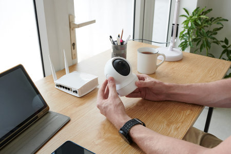 Hands of homeowner installing video camera in his home office