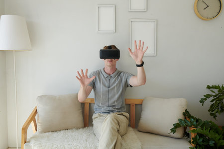 Young man in virtual reality headset touching invisible objects