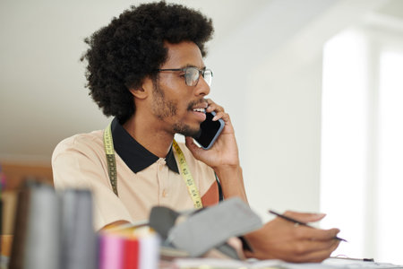 Portrait of fashion designer talking on phone with client