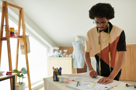 Fashion designer drawing pattern on fabric with blue chalkの写真素材