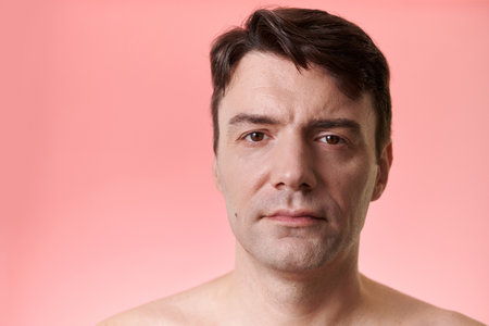 Studio portrait of serious mature man with mole on right cheekの写真素材