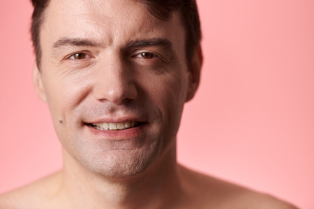 Portrait of happy middle-aged man standing against pink backgroundの写真素材