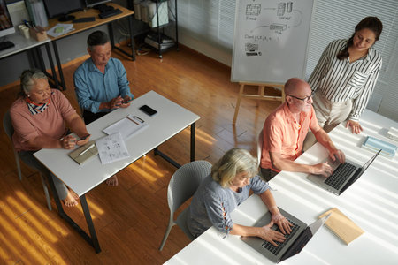 Group of senior men and women attending class of computer training for seniors