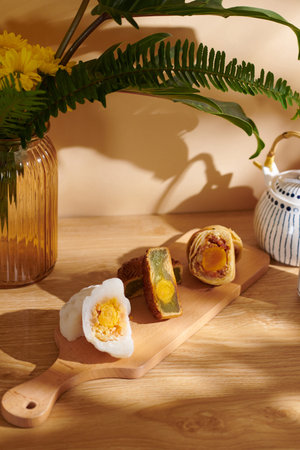 Still life with flower vase, traditional moon cakes with various fillings and tea pot
