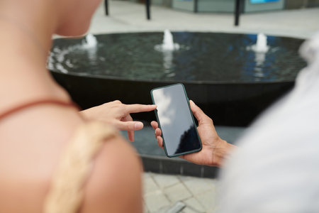 Closeup image of woman pointing on screen of smartphone in hands of coworkerの写真素材
