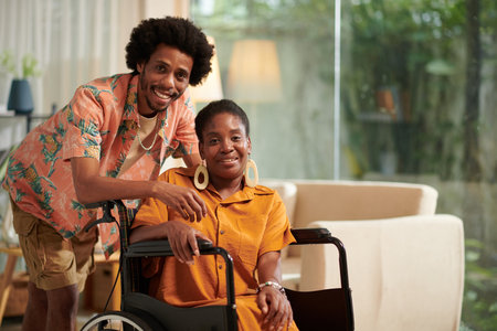 Portrait of smiling Black man and his girlfriend with disability spending time at home togetherの写真素材