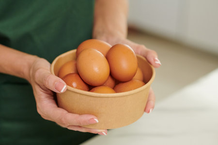 Bowl with fresh rinsed eggs in hands of woman cooking breakfastの写真素材