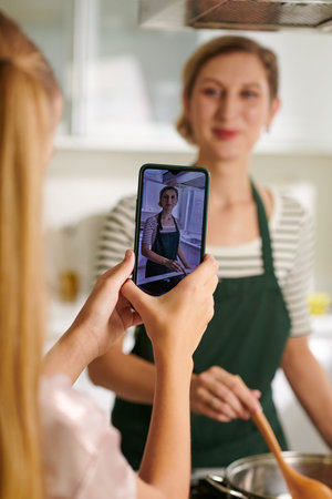 Girl filming short video of her mother cooking for social media