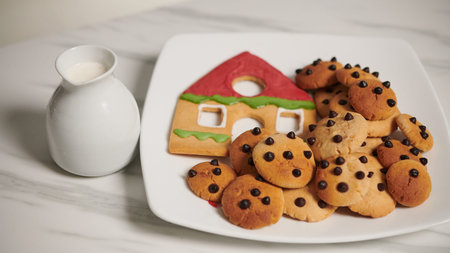 Jar of milk next to plate with gingerbread cookies baked for Christmas