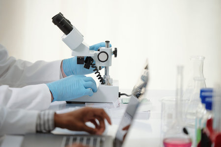 Hands of researcher looking at human tissue with microscope