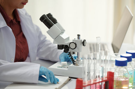 Cropped image of pharmaceutical scientist working with professional microscope in modern lab