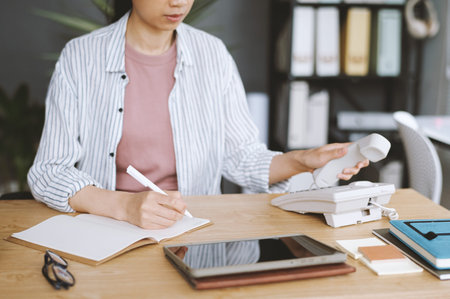 Business manager making phone call when writing in planner in the morning