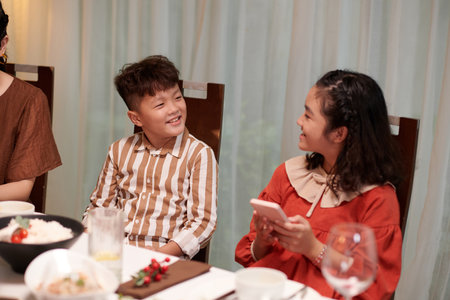 Smiling Vietnamese brother and sister taking at family dinnerの写真素材