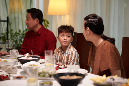 Mother asking child if what he wants to eat when they are sitting at dinner tableの写真素材