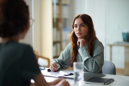 Young HR manager listening to candidate talking about his experienceの写真素材