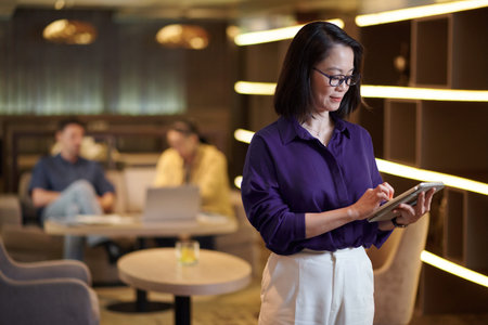 Mature businesswoman filling document on tablet computerの写真素材
