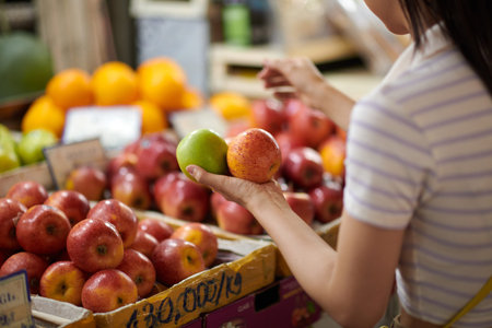 Young woman buying fresh organic fruits at local marketの写真素材