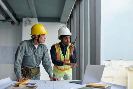 Emotional foreman using walkie-talkie to communicate with team at construction site