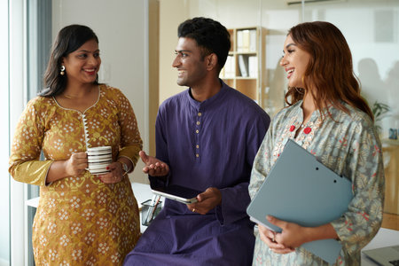 Smiling Indian business colleagues in traditional clothes discussing work during coffee breakの写真素材