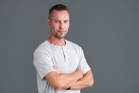 Portrait of confident mature man in grey tshirt crossing arms and looking at camera