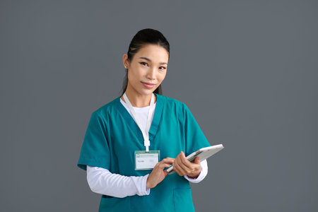 Portrait of smiling Vietnamese medical nurse with digital tabletの写真素材