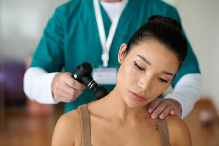 Therapist using massage gun to promote recovery after injury or intense activity by improving blood flow to areaの写真素材