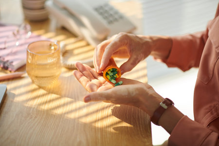 Hands of mature woman taking painkillers or antidepressants before work