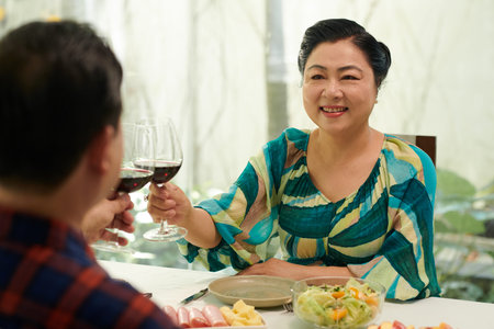 Happy senior woman enjoying romantic dinner with husband at homeの写真素材